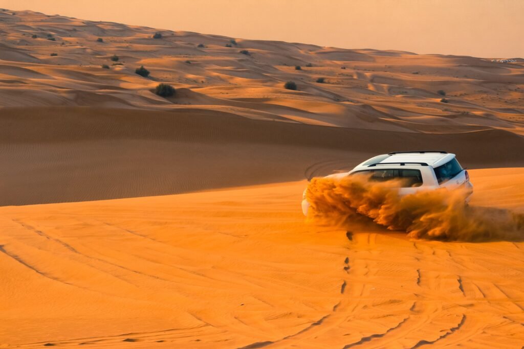 SUV driving through Dubai desert dunes at sunset