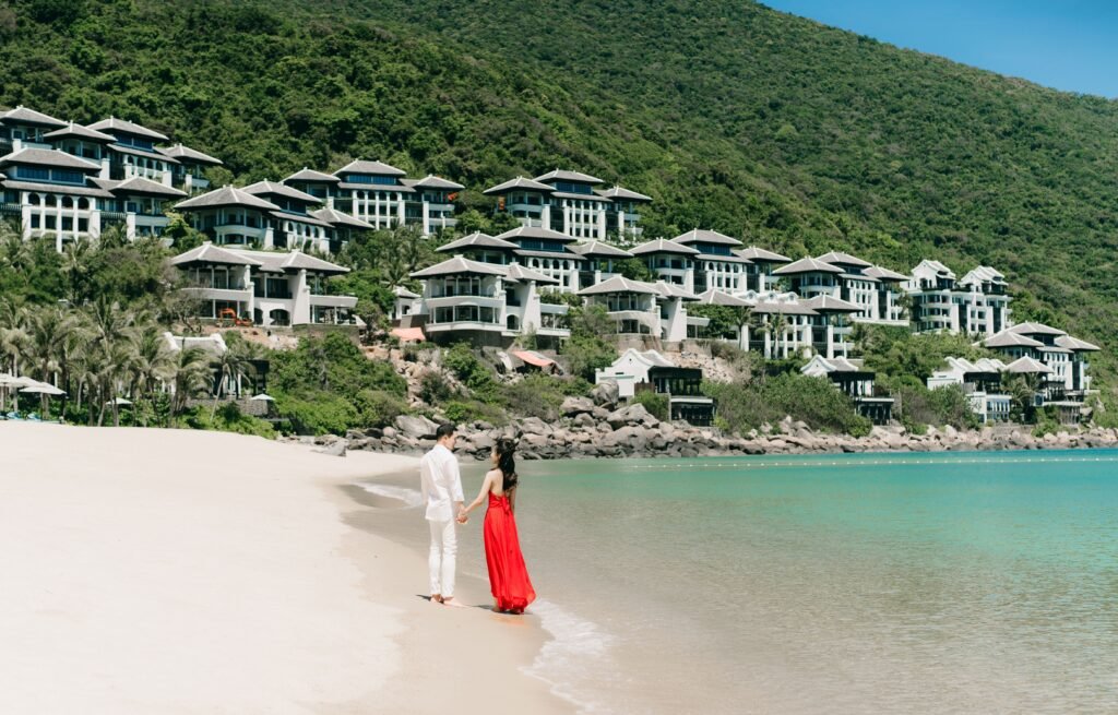 Couple walking hand in hand on a pristine beach near luxury villas
